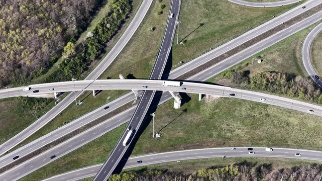 Aerial view of a complex highway interchange with multiple lanes merging and diverging, creating a network of grey roads amidst green fields, Sausheim, Grand Est, France.