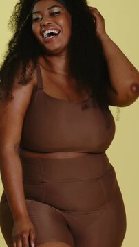 Vertical video: Camera pulling back, model turning and flipping hair in studio, showing brown set