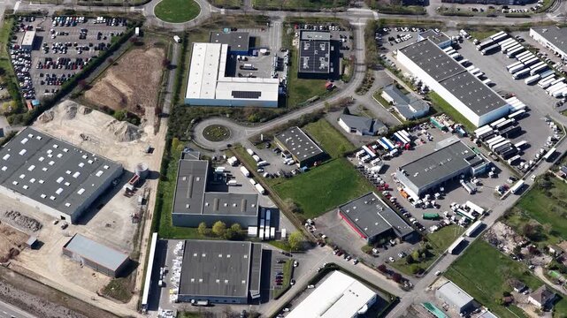 Aerial view of industrial buildings, roundabouts, and many parked vehicles showing organized infrastructure, Sausheim, Grand Est, France.
