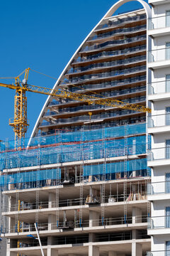 Construction progress on modern Benidorm Spain skyscraper highrise with crane scaffolding and detailed facade rising above the city