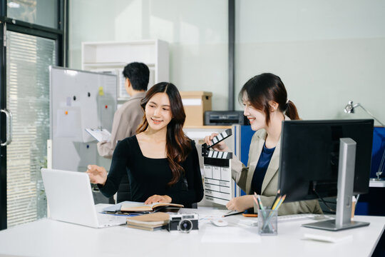 Creative team planning video production in modern office, using clapperboard, laptop and notebook. Business, marketing, content creation