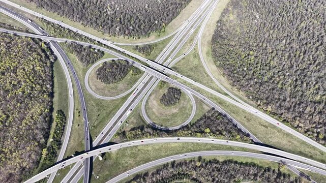 Aerial view of highway interchange cloverleaf design shows the contrast between the man-made structure and the surrounding natural environment, Sausheim, Grand Est, France.