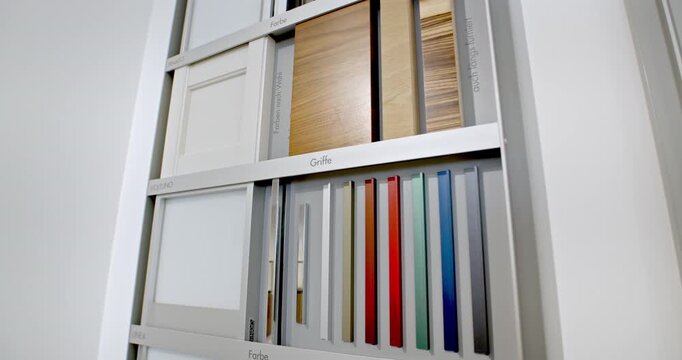 Showroom display featuring various cabinet door styles, wood finishes, and a wide range of colorful handle samples