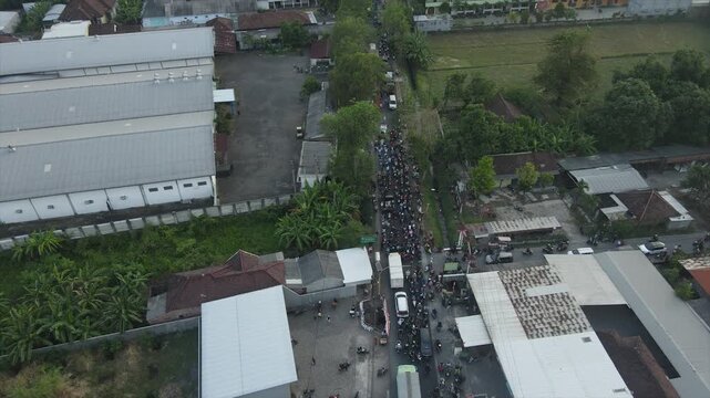 Aerial 4K view of heavy traffic and motorbikes at a busy village intersection in Indonesia.