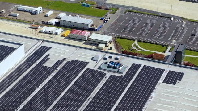 Aerial view of massive logistics distribution centre rooftop with integrated solar panel array and HVAC cooling units.