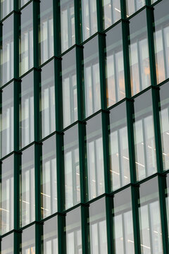 Abstract texture on modern green glass facade where architecture lines form a clean pattern across the building exterior in close detail