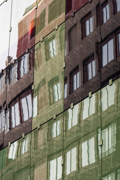 Abstract urban facade where modern glass windows create reflection pattern and layered texture across the architecture of a city building