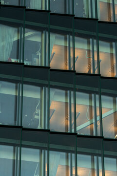 Urban architecture office building with modern facade glass windows and visible interior creating repeating pattern for contemporary corporate scene
