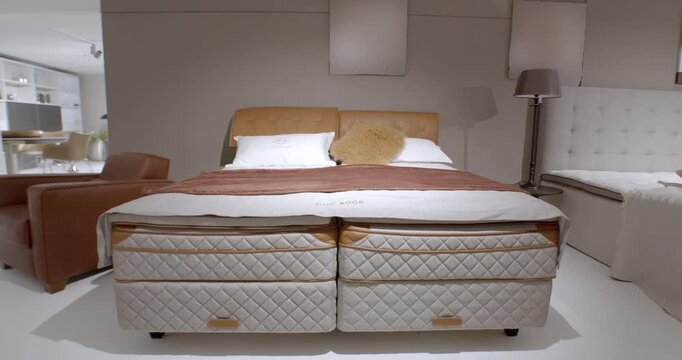 Modern luxury box spring bed with leather headboard and quilted mattress in a furniture showroom
