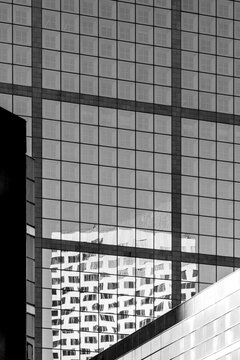 Modern monochrome architecture facade with abstract geometric glass grid reflections at a sharp corner creating sleek corporate exterior detail