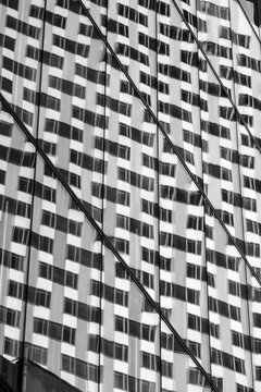 Monochrome abstract architecture building facade with geometric windows grid showing pattern repetition for modern corporate highrise texture detail