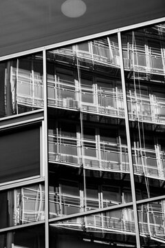Monochrome architecture building facade with abstract geometric glass reflections over grid lines creating sharp modern corporate exterior detail