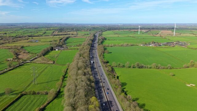 Aerial  view of heavy traffic on the M1 motorway with wind turbines and green fields in the distance UK