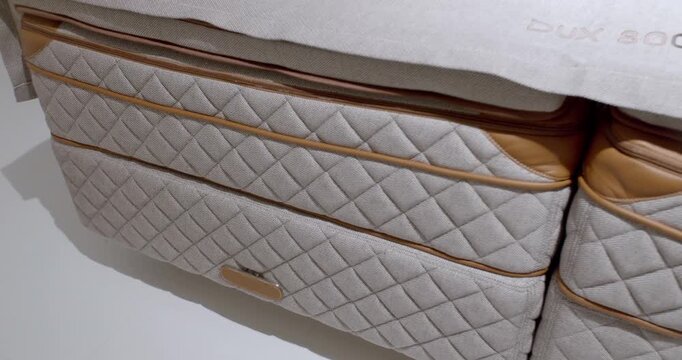 Close up of luxury quilted mattress with beige textile and tan leather trim in a modern bedroom showroom