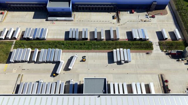 Top down aerial view of HGV trucks parked in loading bays at a logistics hub, UK