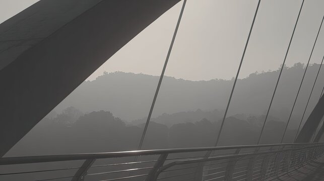 Modern architectural bridge featuring an arched structure and support cables, spanning across a valley with layers of mountains fading into a light mist