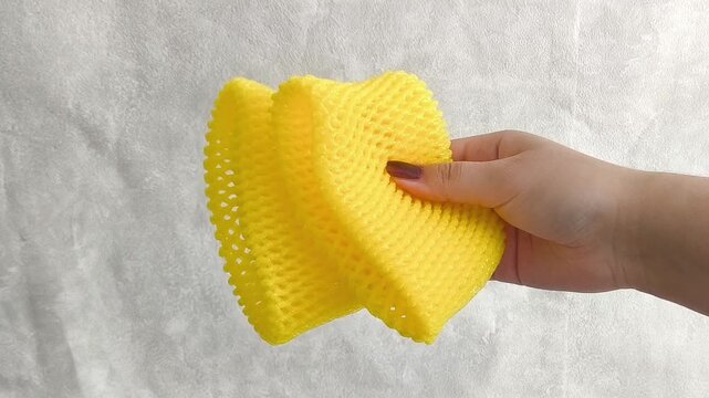 Yellow foam net for fruit in hand. Packaging for transportation, delivery of vegetables