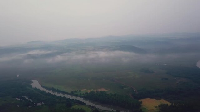 Aerial view of misty Karli River meandering through green wetlands and farmland in Malvan region, Konkan coast, Maharashtra, India.