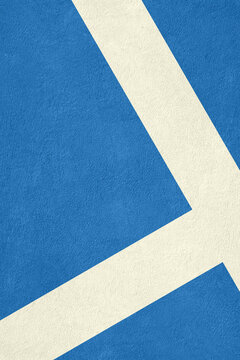 A top-down close-up view of a blue synthetic sports court surface featuring crisp white painted boundary lines and a granular texture