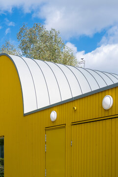 Curved roof warehouse architecture against sky showing yellow building and door in minimal industrial style for clean abstract background detail