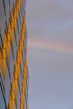 Modern building architecture with glass facade showing rainbow color in sky reflection forming abstract pattern and calm urban design detail