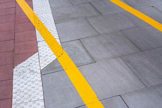 Urban safety texture pattern with tactile crossing line on sidewalk pavement in yellow creating abstract minimal accessibility street design detail