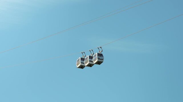 Three static cable cars suspended against clear blue sky