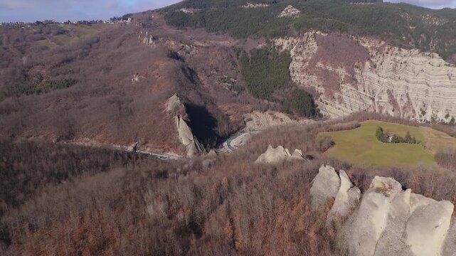 Pan left aerial revealing dramatic Salti del Diavolo rock formation in Parma Apennines landscape.