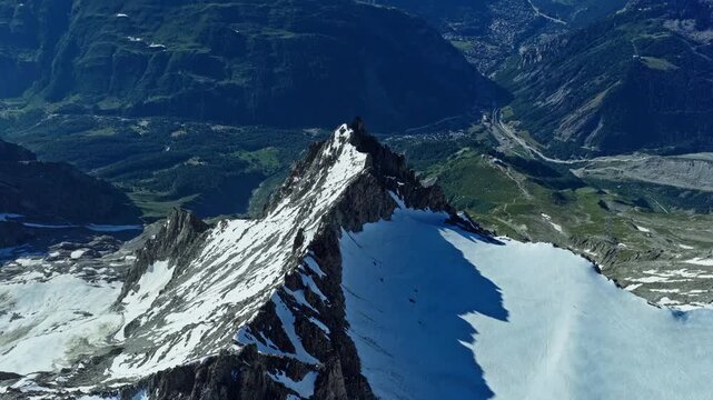 cinematic dolly forward aerial shot capturing a rugged granite peak and pristine snowfields in the Chamonix Alps, France, showcasing the dramatic high-altitude landscape of the Mont Blanc massif