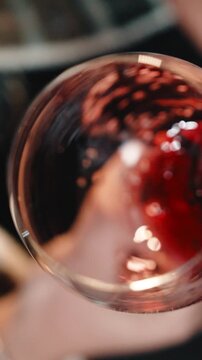 Wine is falling into a glass of red wine with splashes. Slow mo