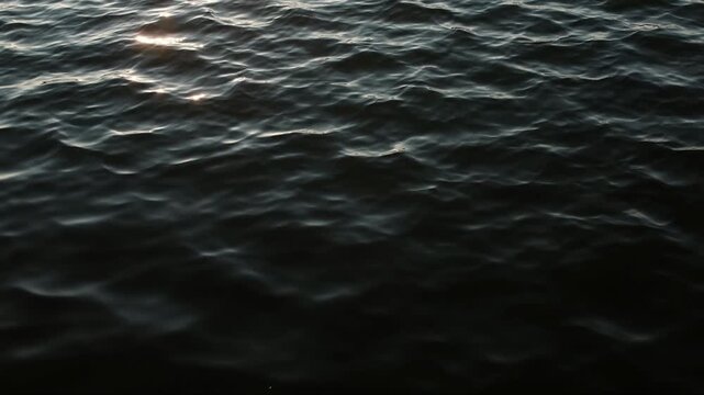Dark mysterious video of slow breeze on water. Still lake water and small waves.

