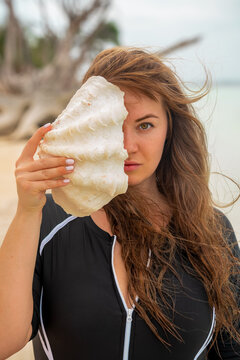 Giant Seashell by Woman&rsquo;s Face on Beach,Artistic Portrait
