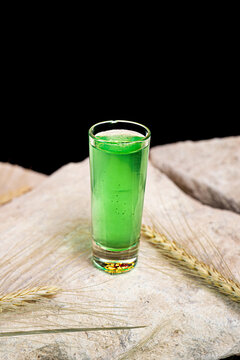 Green absinthe alcoholic drink in shot glass isolated on black background.