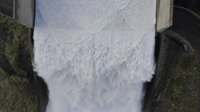 Drone flies backwards with camera straight down over bottom of spillway at Mohale Dam on the Senqunyane River on a late afternoon in the mountains of Lesotho
