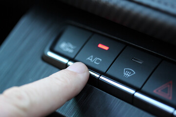 Close up of a finger pressing the A/C button in a modern vehicle © hanjosan
