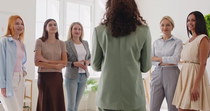Women group meeting for team training and leadership. Female coach in green leads a workshop in a bright office, while the business team listens. Concept leadership, teamwork, and diversity.