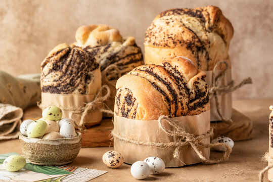 Easter cakes cruffins (Kulich) with poppy seed filling on beige textured background. Easter bread, easter eggs