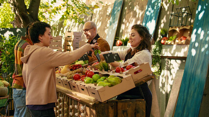 Young vendor giving free apple samples to clients, having fun with fresh products sampling at local...