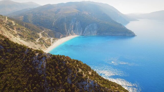 Aerial view of Myrtos Beach in Kefalonia by lush hills and blue summer sea