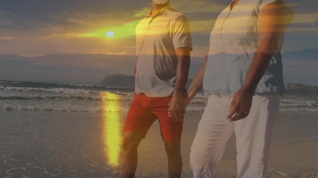 mature couple walking on sand holding hands, sun drawing them, lens flare gliding over them travel