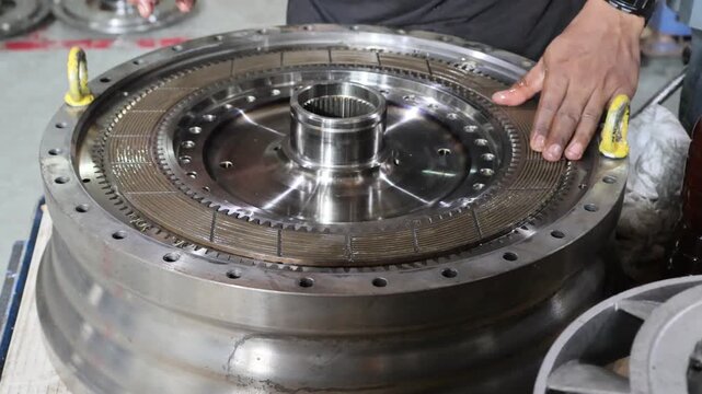 Professional mechanic assembling a clutch lock-up plate into an automatic transmission torque converter system inside an industrial workshop.