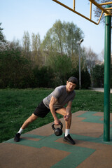Obraz premium Man Training with 16 kg Kettlebell at Outdoor work out Area