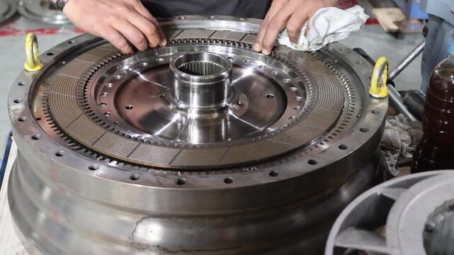 Professional mechanic assembling a clutch lock-up plate into an automatic transmission torque converter system inside an industrial workshop.