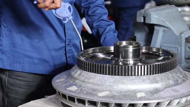 Technician hand cleaning heavy duty automatic transmission parts using air blow gun tool in a professional mechanical workshop garage.