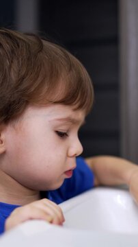 Lovely cute toddler standing at the sink in the bathroom. Caucasian boy opens and closes the tap. Close up.