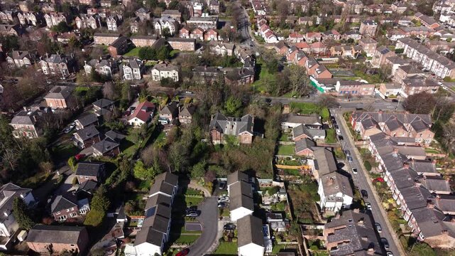 4K aerial video showing Birkenhead Merseyside with suburban rooftops and tree covered residential areas.