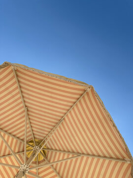 Sunshade blue sky beach umbrella. Sun umbrella with yellow and biegh stripes.