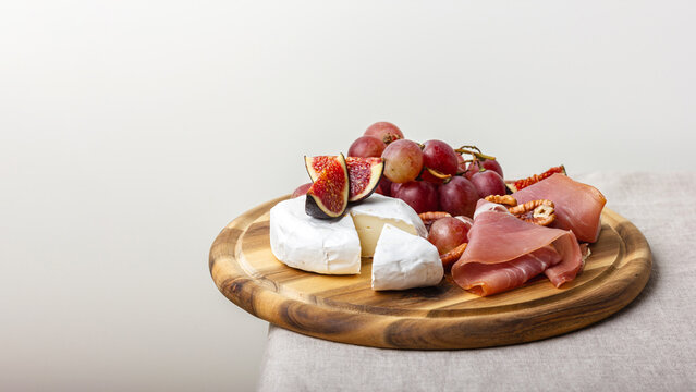 Charcuterie board with meat, cheese, grapes, nuts and fresh figs.