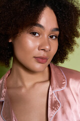 Young woman shines in stylish pink attire against a vibrant green backdrop © LIGHTFIELD STUDIOS