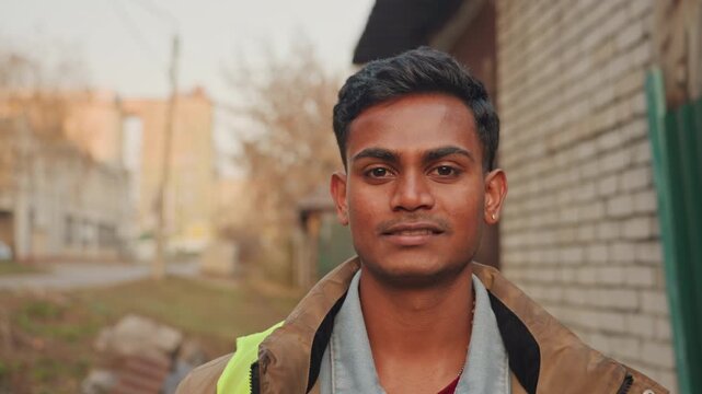 Profile repair inspector looking sideways young male maintenance worker glancing toward alley, contemplative expression, soft autumn light, brick residential backdrop, planning next repair task,